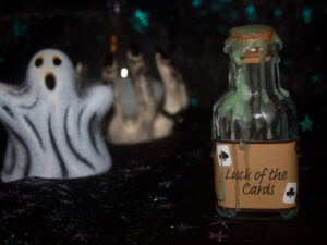 A product photo of a spell jar with the label "Luck of the cards" in the right background is a ceramic ghost and hourglass.