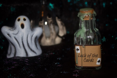 A product photo of a spell jar with the label "Luck of the cards" in the right background is a ceramic ghost and hourglass.