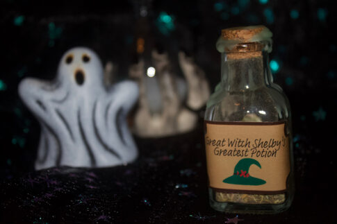 A product photo of a spell jar with the label "Great Witch Shelby's Greatest Potion" in the right background is a ceramic ghost and hourglass.