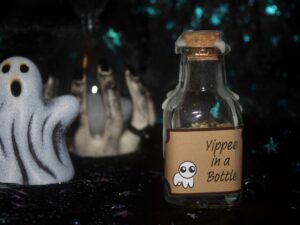 A product photo of a spell jar with the label "Yippee in a bottle" in the right background is a ceramic ghost and hourglass.